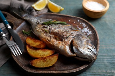 Delicious baked fish served on wooden rustic table, closeup. Seafood