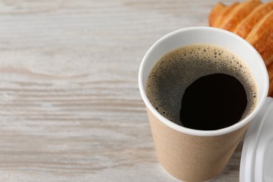 Coffee to go. Paper cup with tasty drink on white wooden table, closeup. Space for text