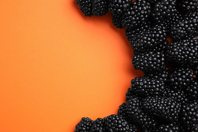 Tasty ripe blackberries on orange background, flat lay. Space for text
