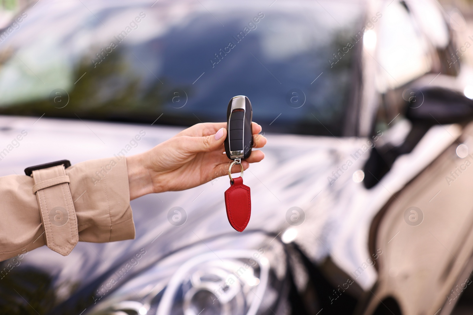 Photo of Woman holding car flip key near her vehicle outdoors, closeup