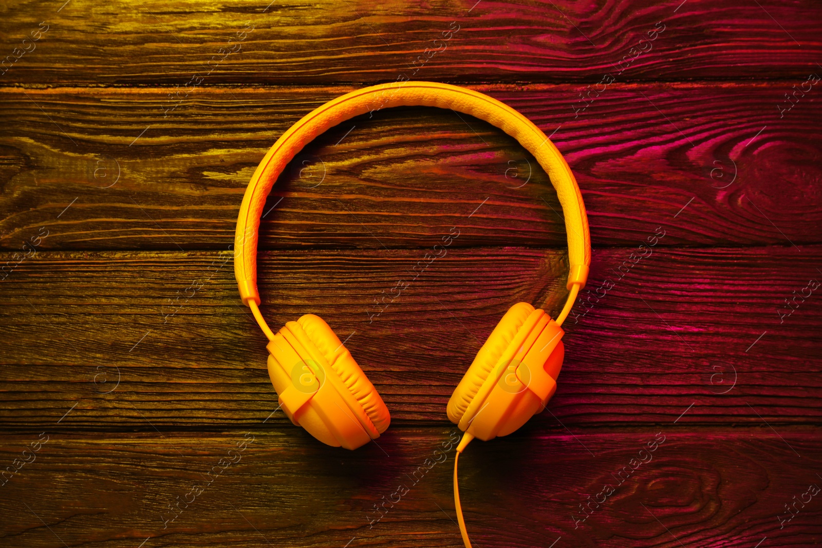 Photo of Stylish modern headphones with earmuffs on wooden background, top view