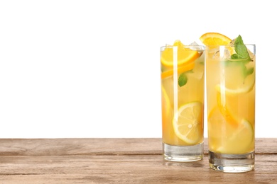 Photo of Glasses of citrus refreshing drink on wooden table against white background