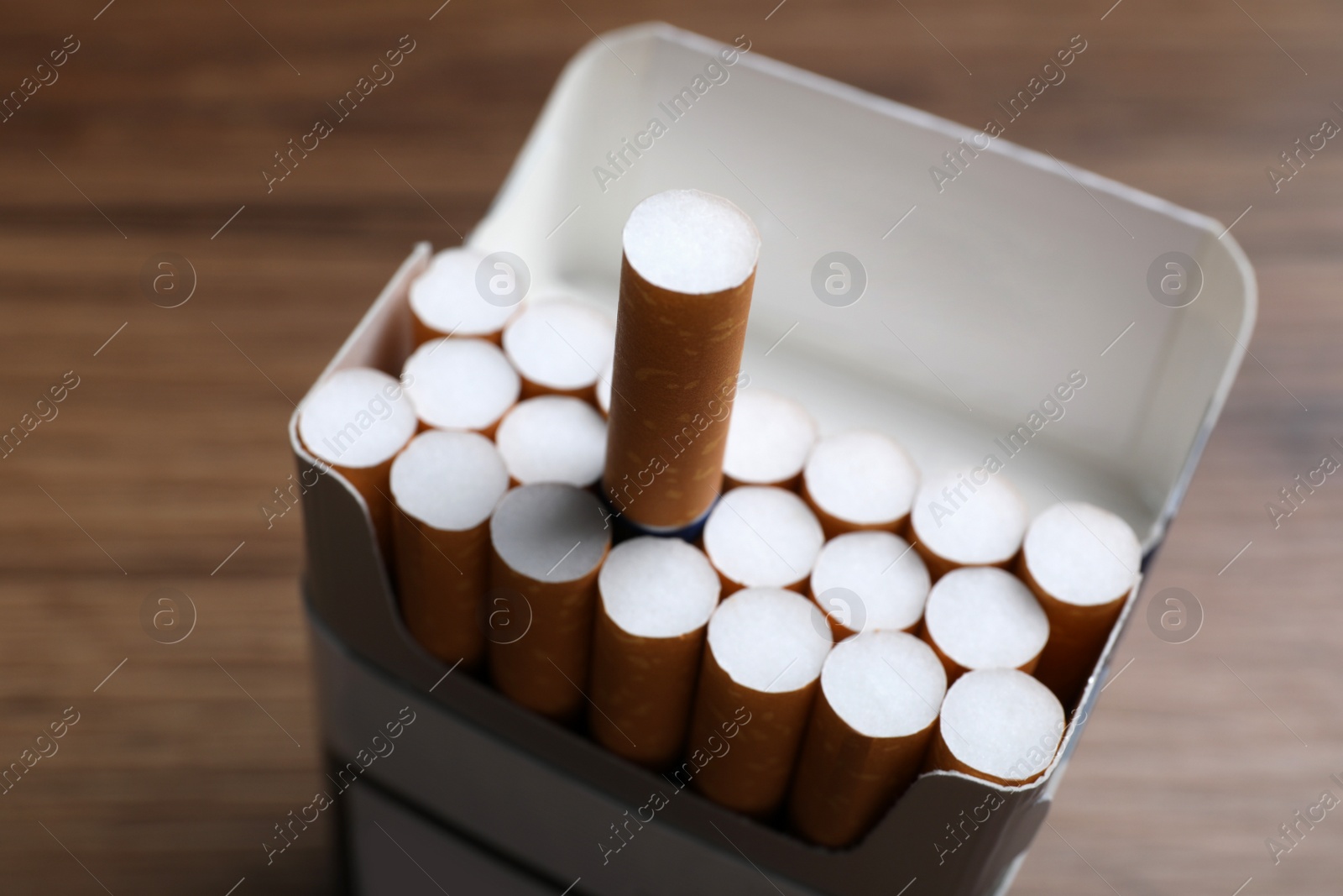 Photo of Cigarettes with orange filters in pack on table, closeup