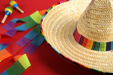 Photo of Mexican sombrero hat and maracas on red background, closeup