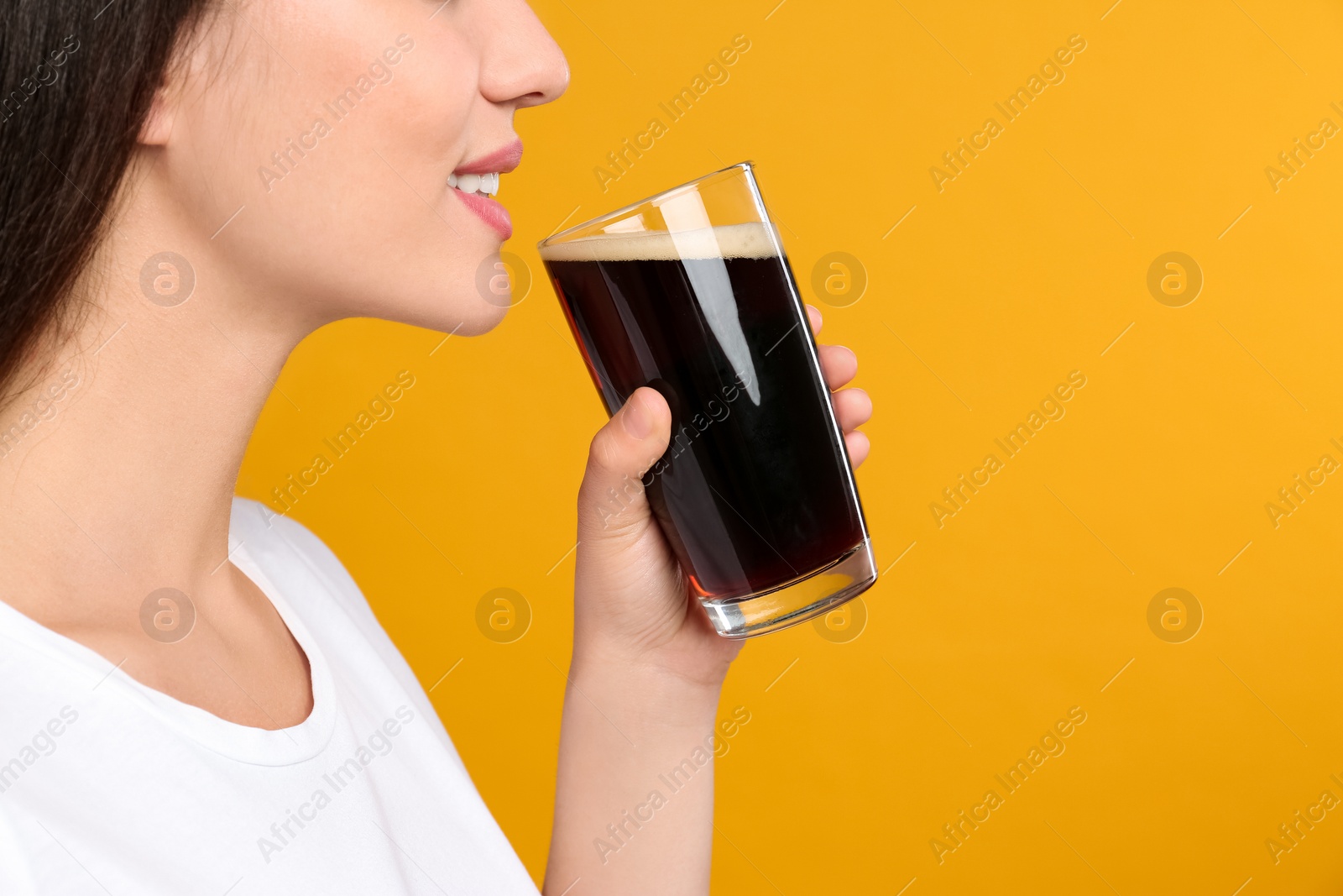 Photo of Young woman with cold kvass on yellow background, closeup. Traditional Russian summer drink