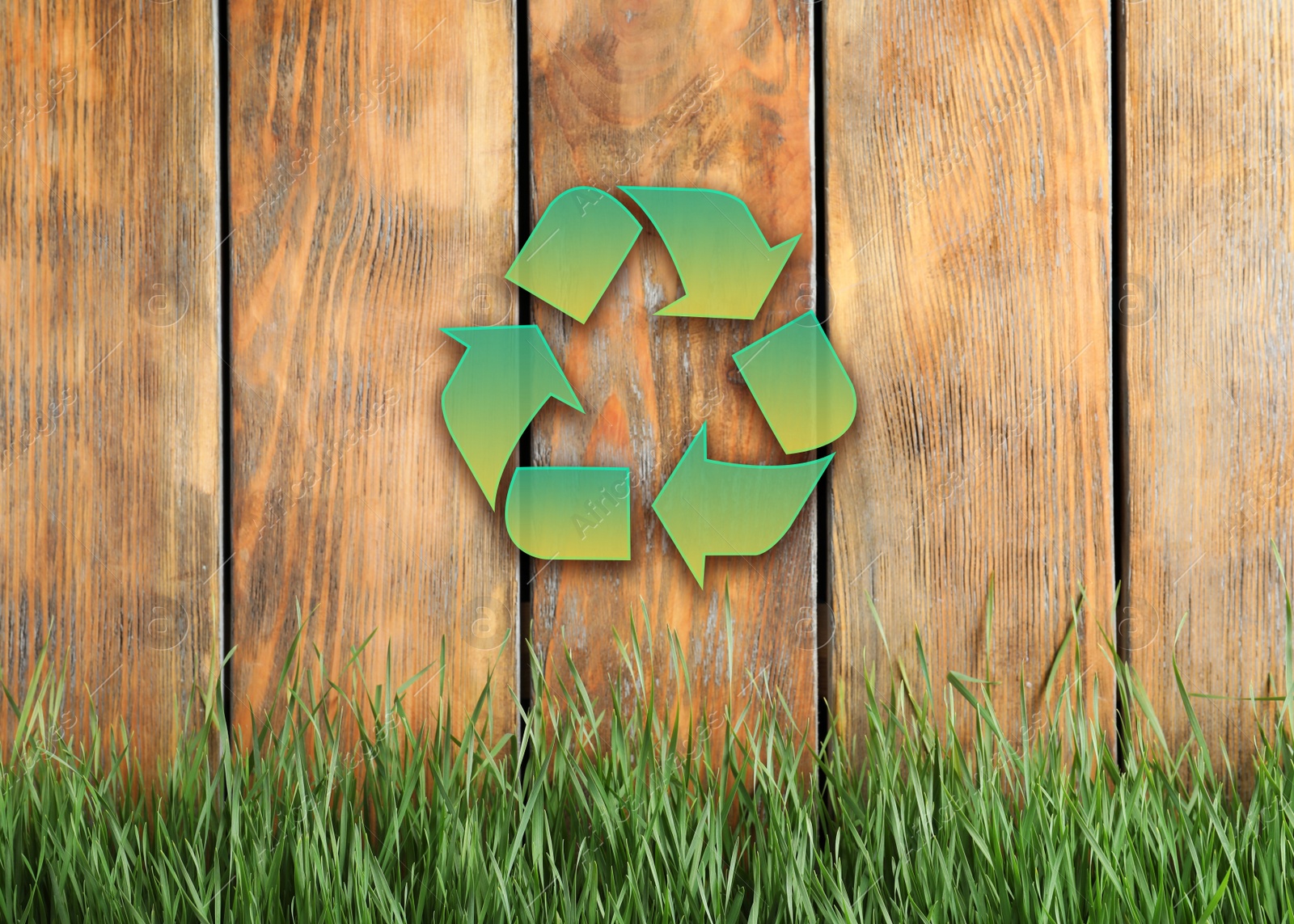 Image of Green grass and illustration of recycling symbol on wooden fence