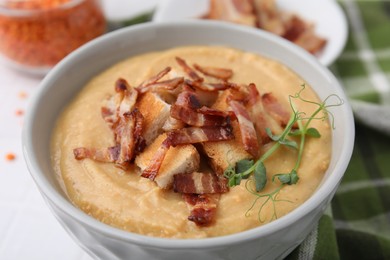 Photo of Delicious lentil soup with bacon and croutons on table, closeup