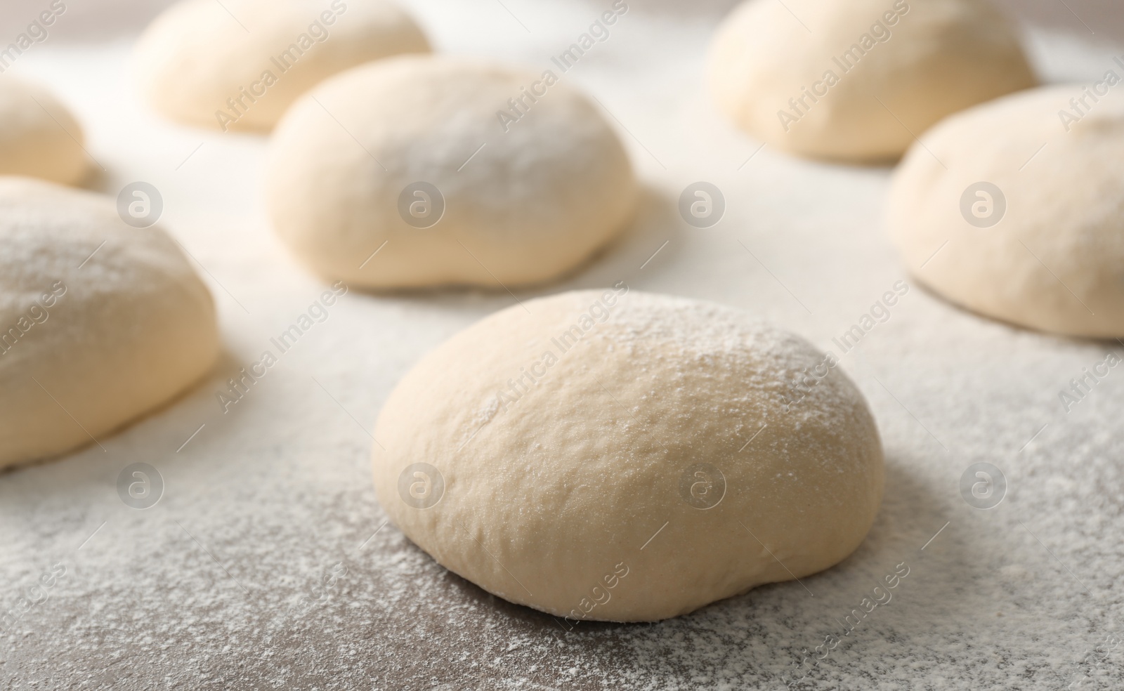 Photo of Fresh raw dough with flour on table