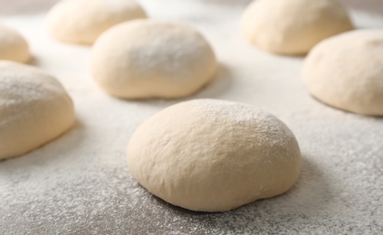 Photo of Fresh raw dough with flour on table