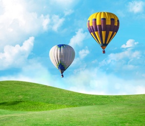Image of Fantastic dreams. Hot air balloons in blue sky with clouds over green meadow 