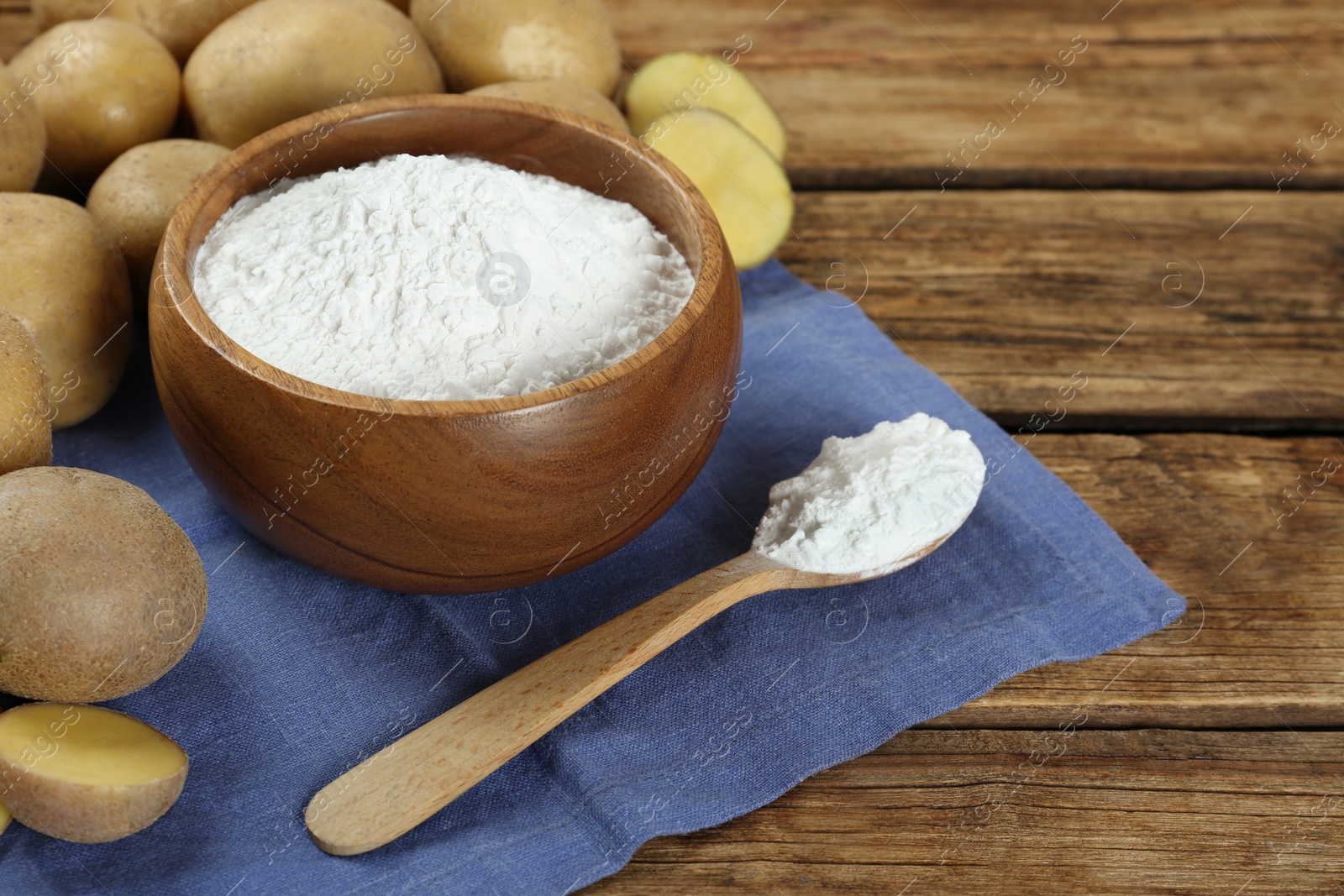 Photo of Starch and fresh raw potatoes on wooden table