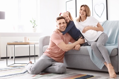 Young pregnant woman with her family at home