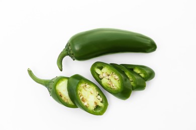 Whole and cut green hot chili peppers on white background, flat lay