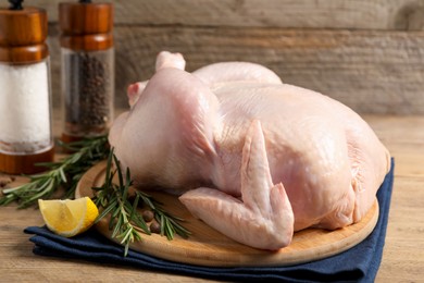 Photo of Fresh raw chicken with spices and lemon on wooden table, closeup