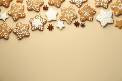 Tasty Christmas cookies with icing and anise stars on beige background, flat lay. Space for text