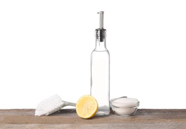 Natural cleaning products. Vinegar in bottle, baking soda, lemon and brush on wooden table against white background