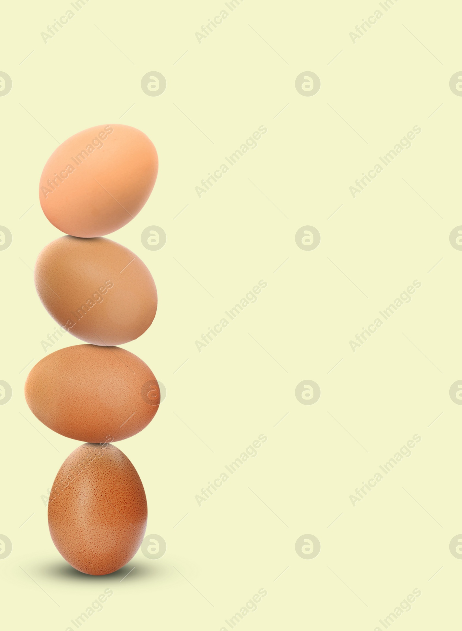 Image of Stacked fresh chicken eggs against light beige background. Space for text