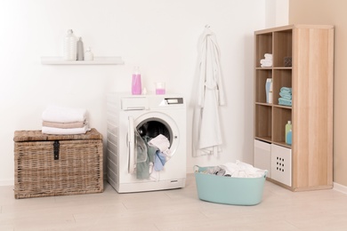 Washing machine with dirty clothes and towels in laundry room