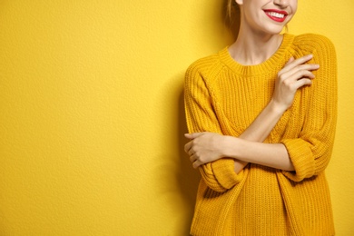 Photo of Beautiful young woman in warm sweater on color background. Space for text