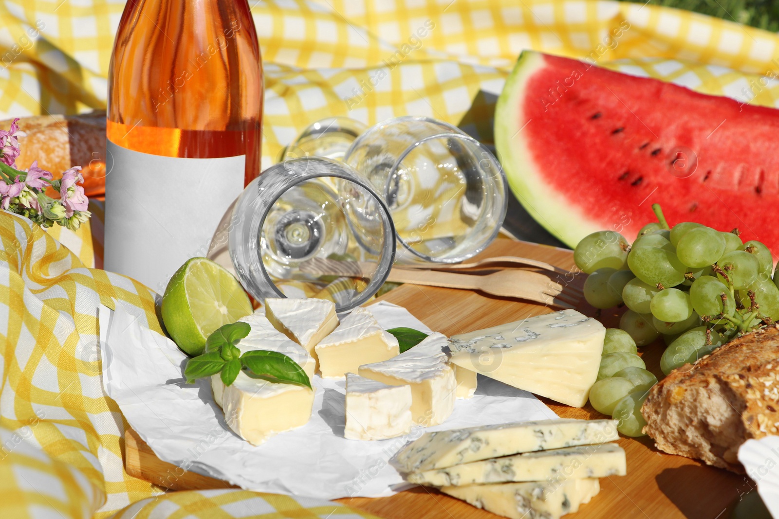 Photo of Delicious food and wine on picnic blanket, closeup