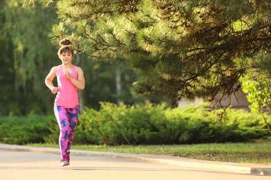 Photo of Young woman running in park on sunny day