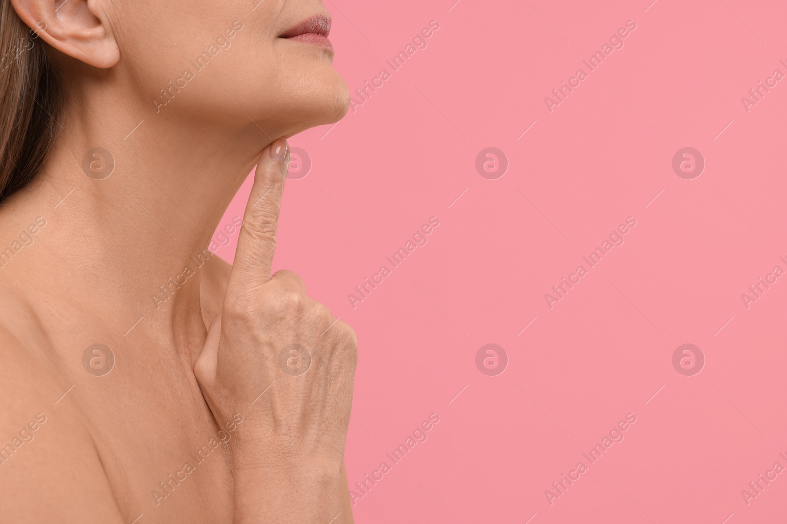 Photo of Mature woman with healthy skin on pink background, closeup. Space for text