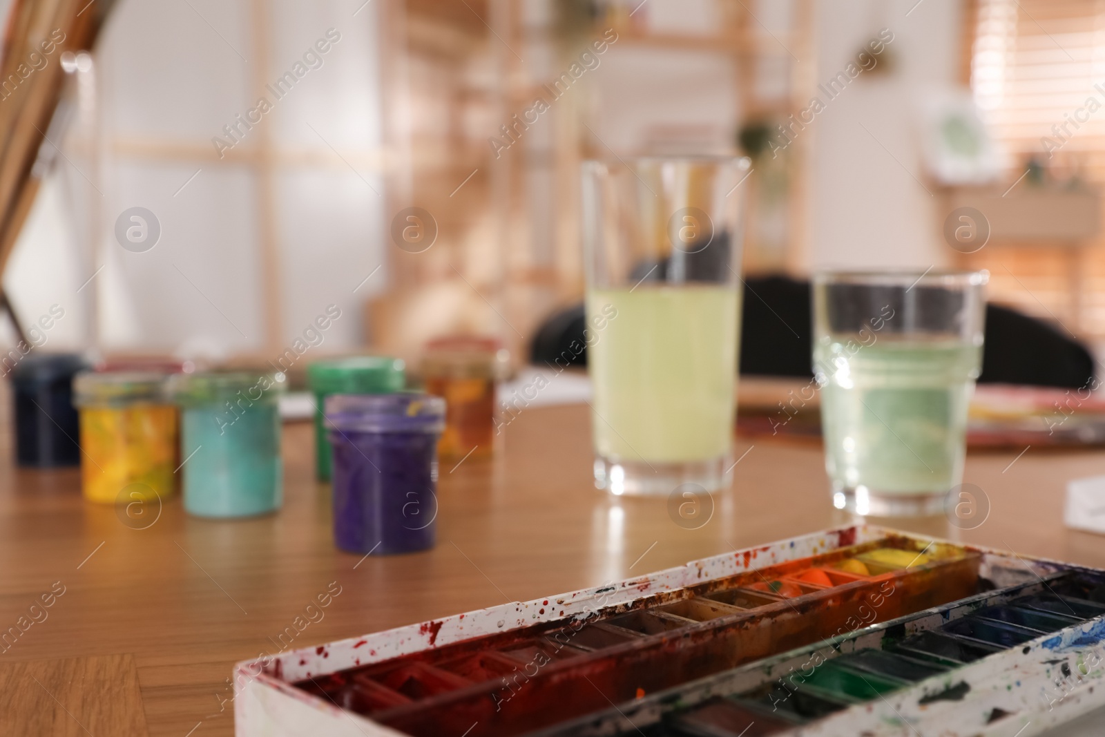 Photo of Paints on wooden table in art studio, closeup. Space for text
