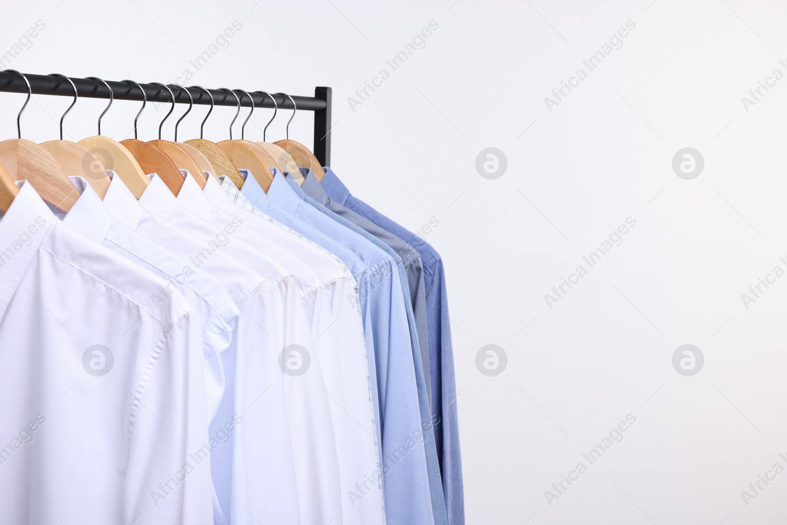 Photo of Dry-cleaning service. Many different clothes hanging on rack against white background, space for text