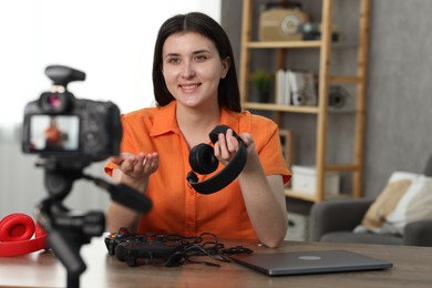 Photo of Smiling technology blogger with headphone recording video review at home