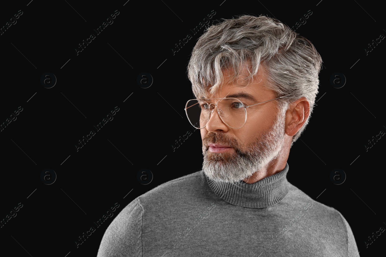 Photo of Portrait of confident man with beautiful hairstyle on black background