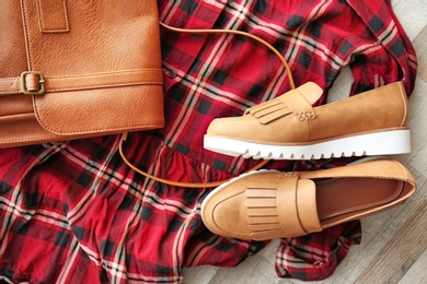 Stylish female shoes, dress and bag on wooden floor