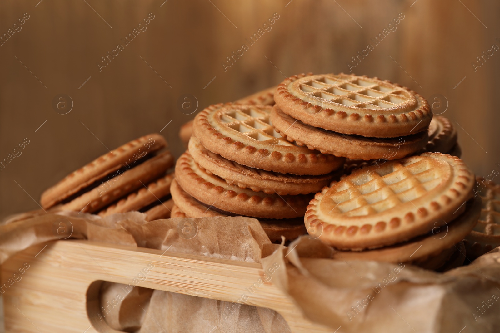 Photo of Tasty sandwich cookies with cream in wooden tray, closeup