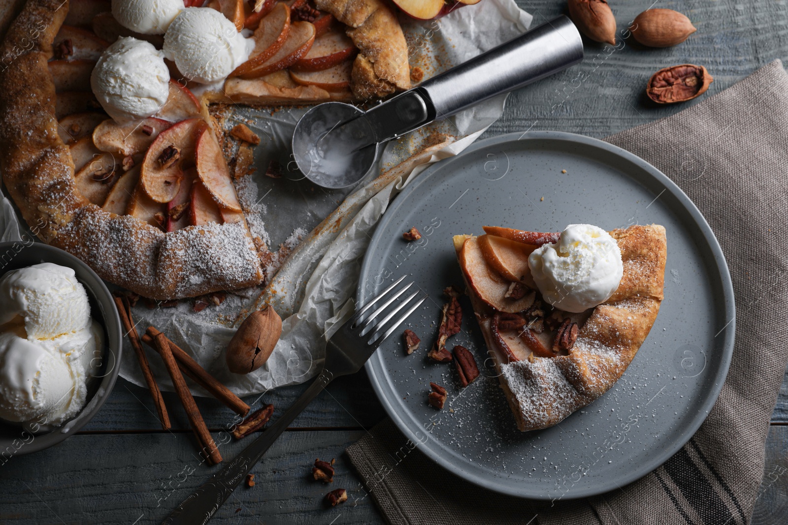 Photo of Delicious apple galette with ice cream and pecans on wooden table, flat lay