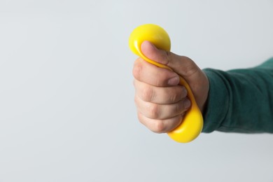 Photo of Man squeezing antistress ball on light background, closeup. Space for text