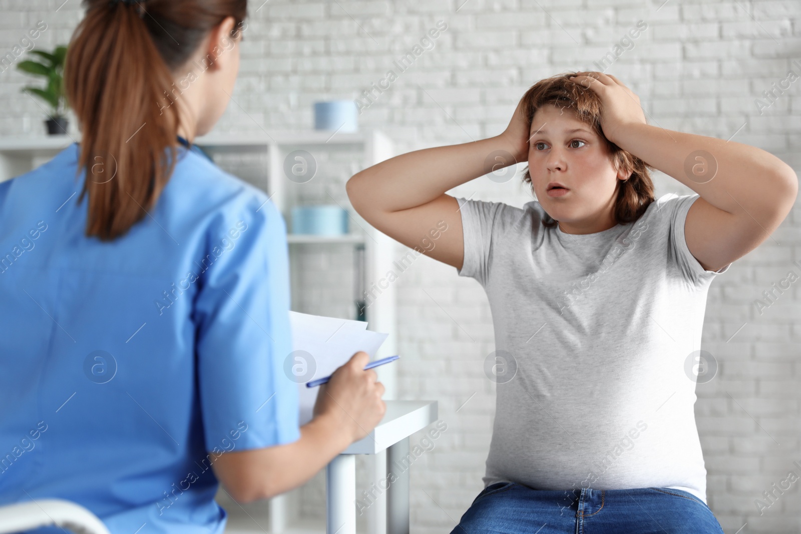 Photo of Emotional overweight boy consulting with doctor in clinic