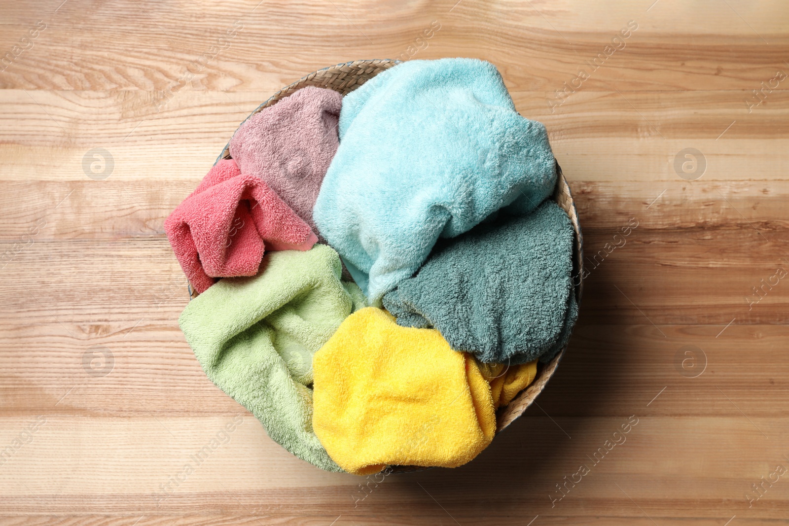 Photo of Wicker basket with laundry on wooden surface, top view