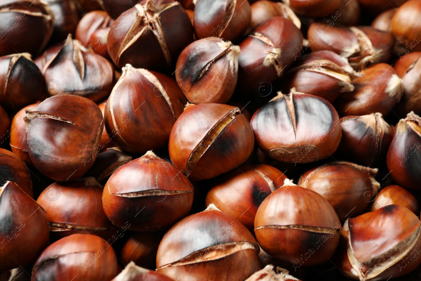 Photo of Pile of delicious edible roasted chestnuts as background, closeup