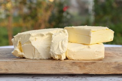 Photo of Board with tasty homemade butter on wooden table outdoors, closeup