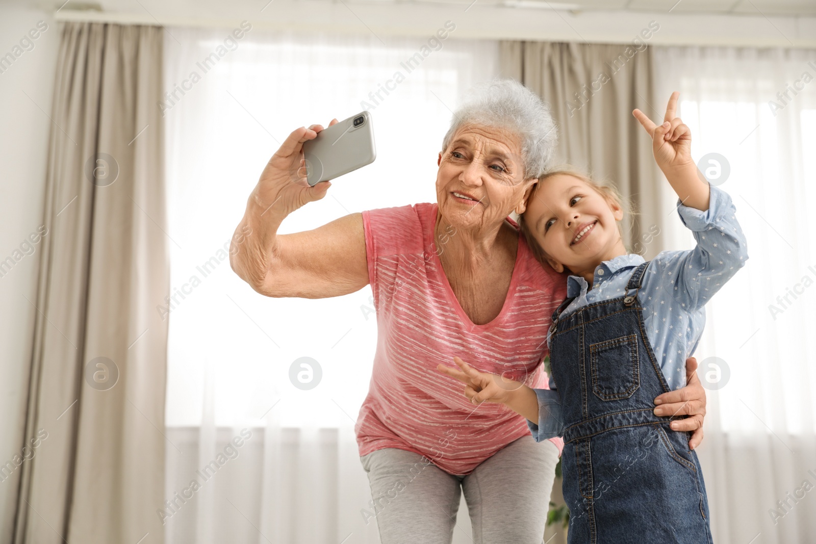 Photo of Cute girl and her grandmother taking selfie  at home