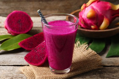 Photo of Glass of tasty pitahaya smoothie and fresh fruits on wooden table