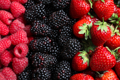 Mix of different ripe tasty berries as background, top view