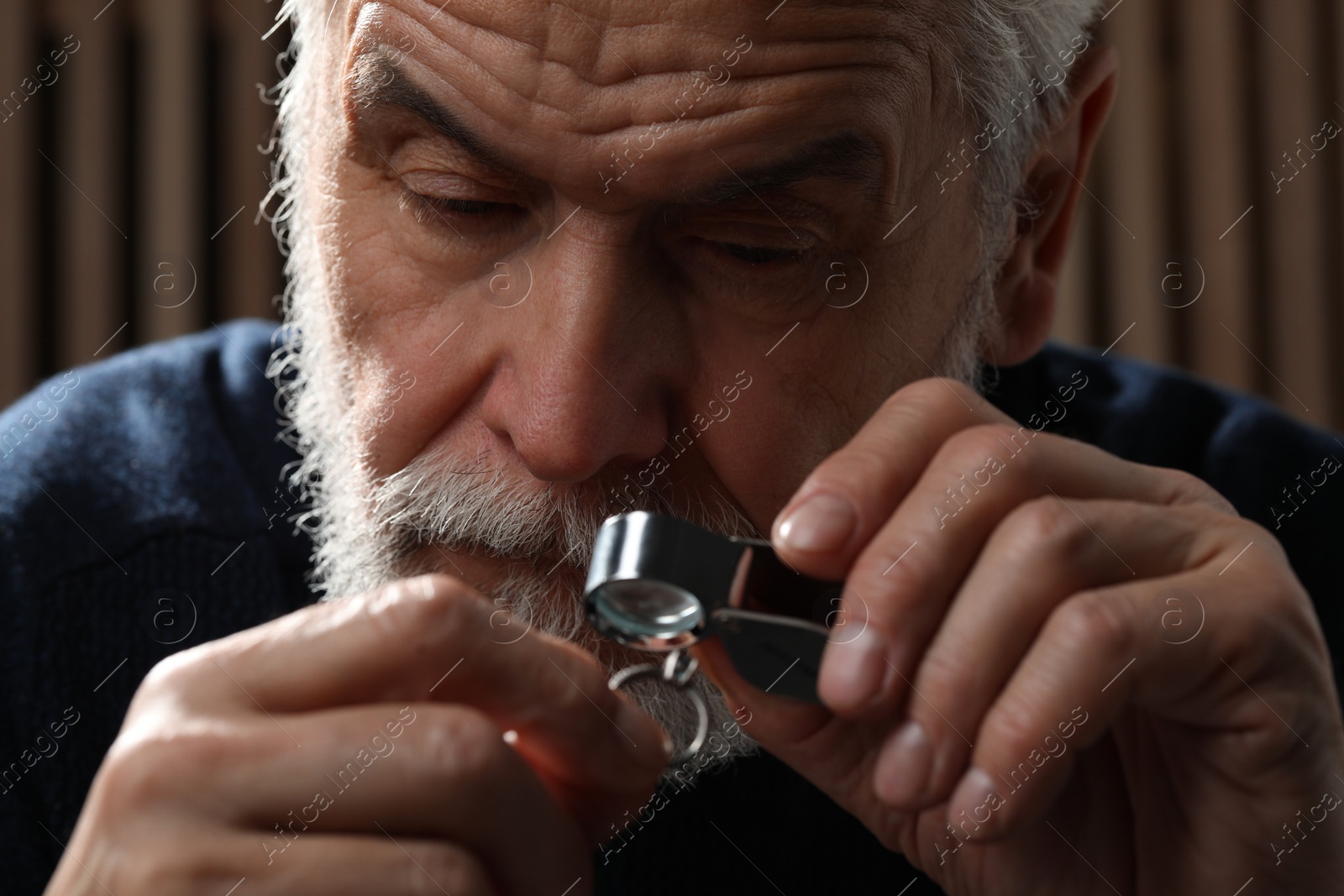 Photo of Professional jeweler working with ring on dark background, closeup