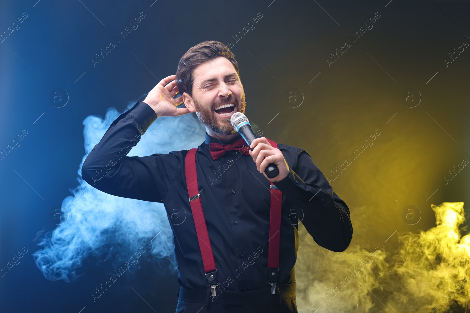 Photo of Emotional man with microphone singing in color lights