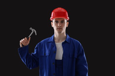 Professional repairman holding hammer on black background
