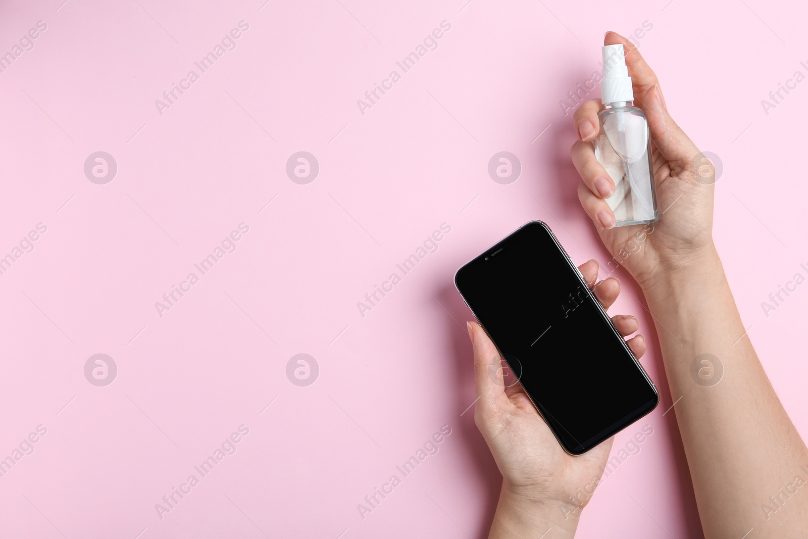 Photo of Woman with smartphone and antiseptic spray on pink background, top view. Space for text