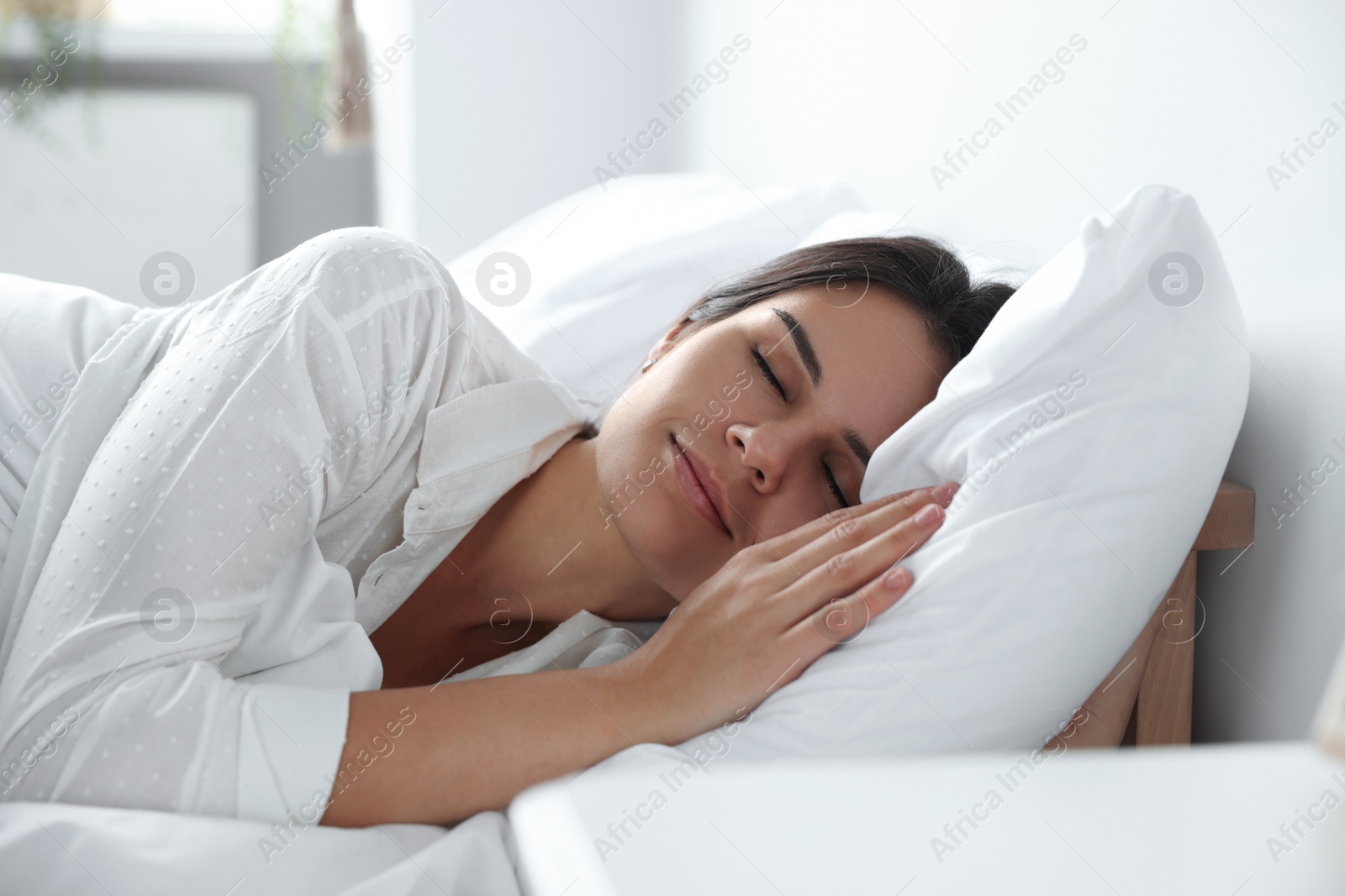 Photo of Beautiful young woman sleeping on soft pillow in bed at home