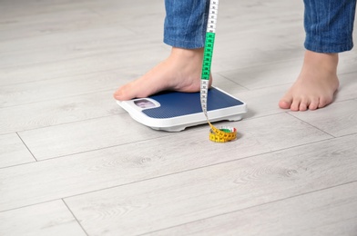 Photo of Overweight woman using scales indoors