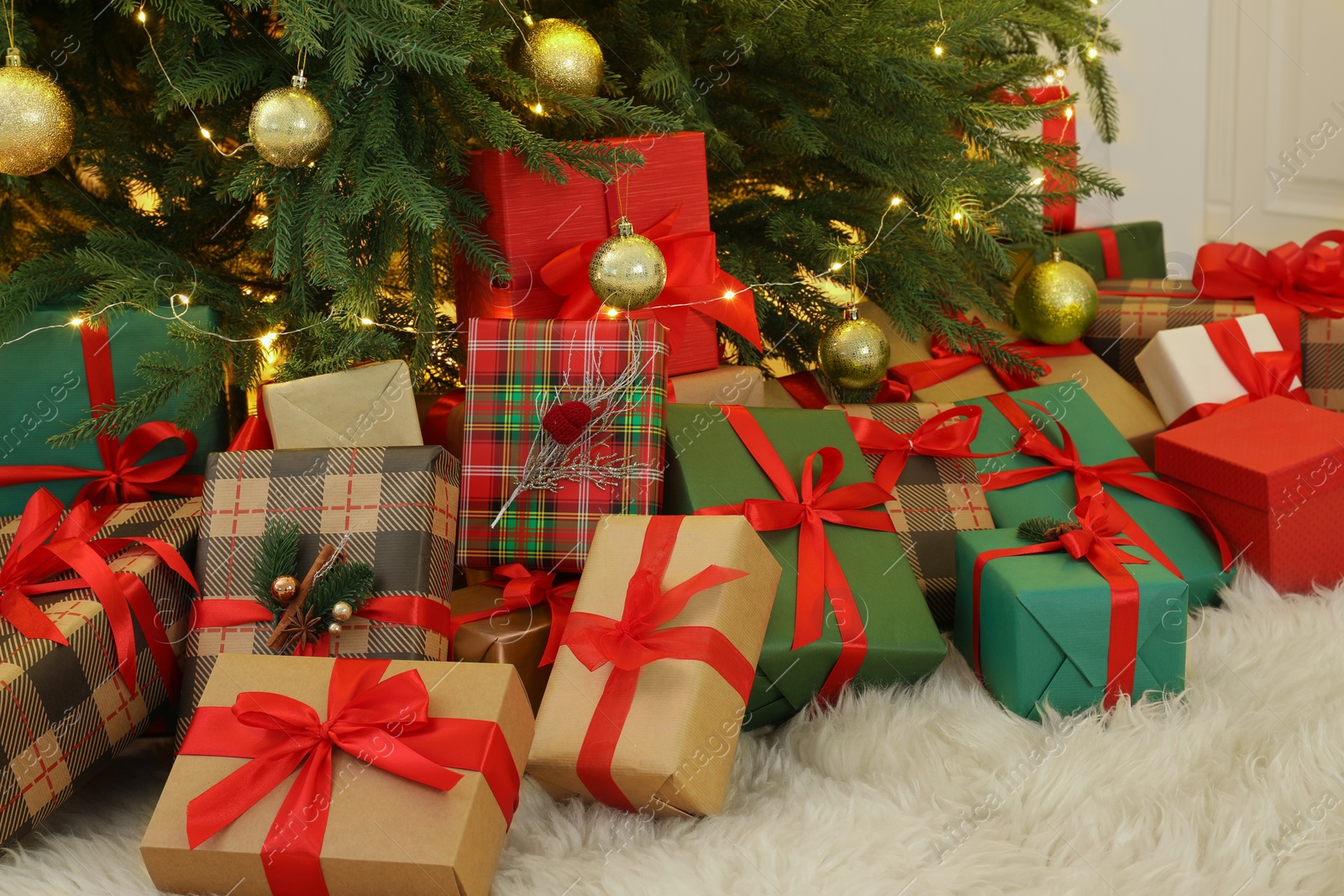 Photo of Many gift boxes under beautiful Christmas tree in room