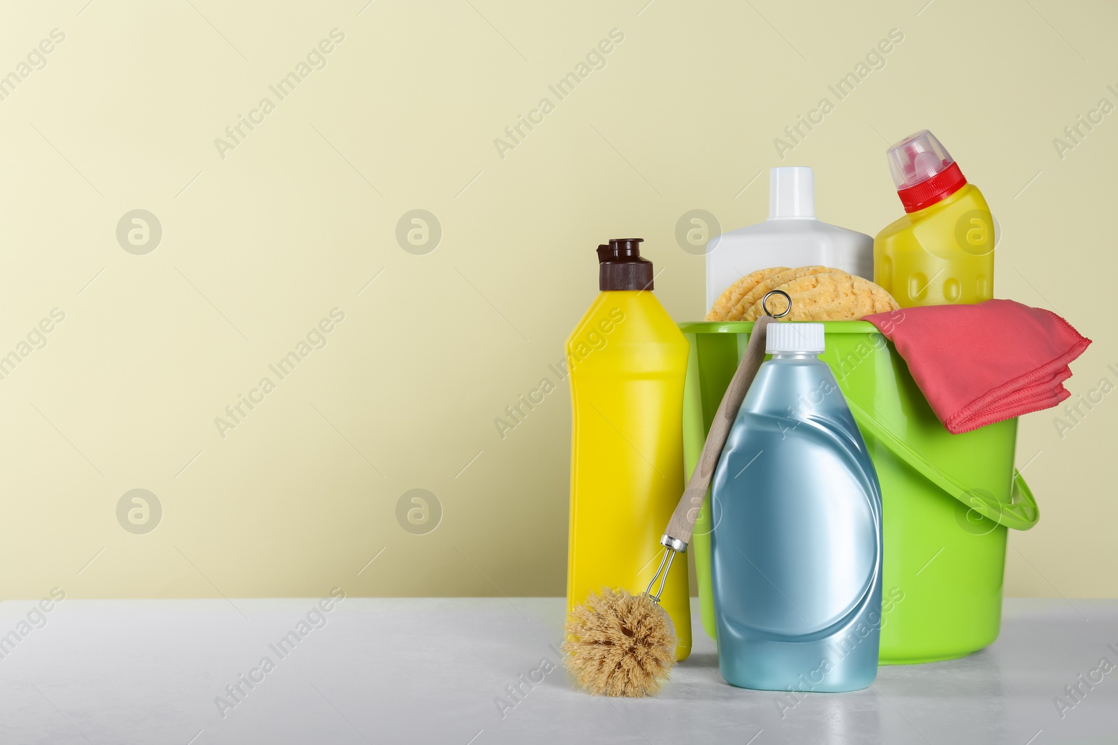 Photo of Different cleaning supplies and tools on table against beige, space for text