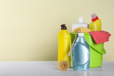 Photo of Different cleaning supplies and tools on table against beige, space for text